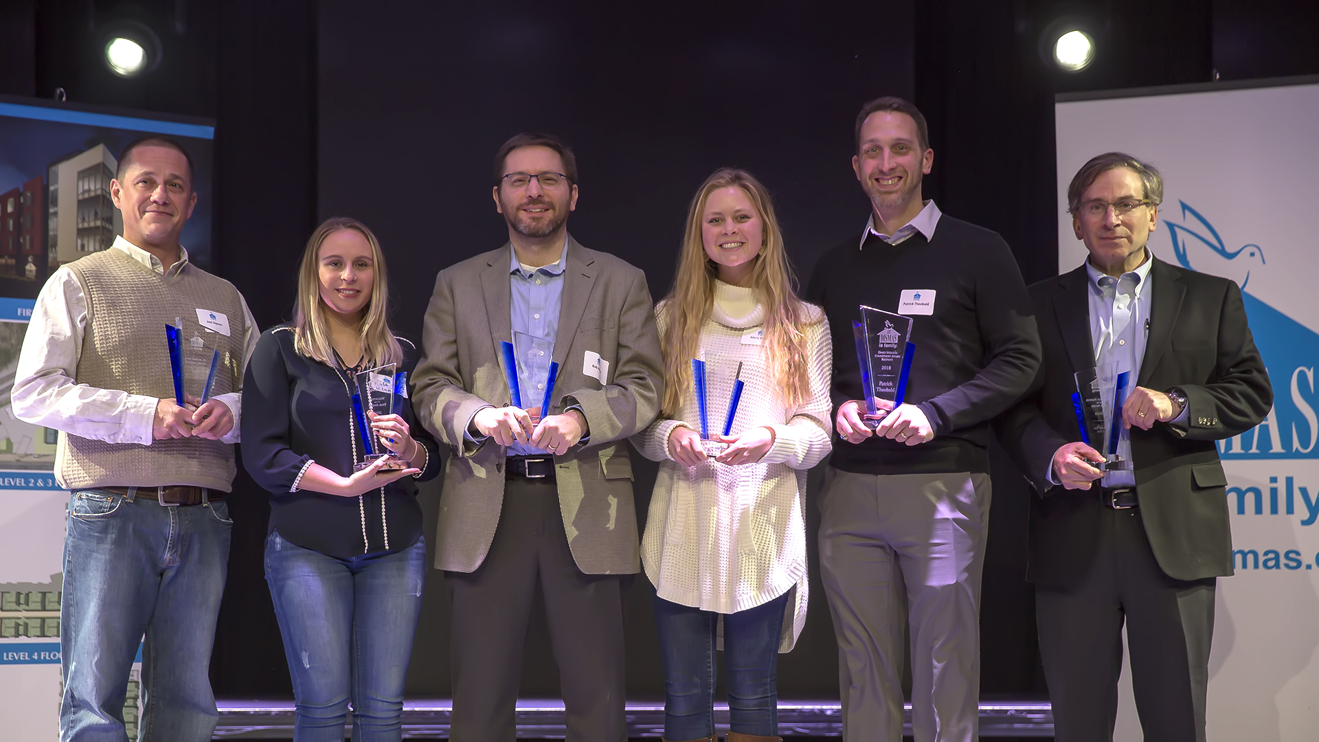 Six individuals standing together with volunteer appreciation awards